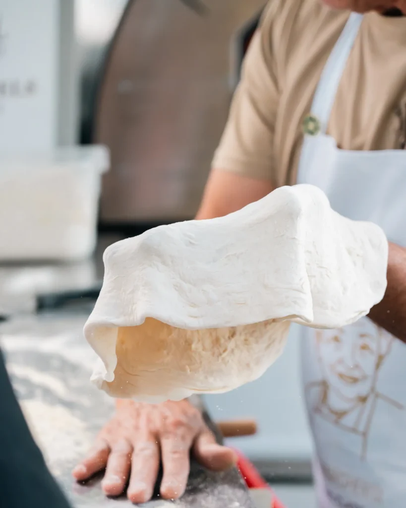 margherita_cooking_class-shoot_01-verticale-2 Impasto per pizza steso a mano durante la Margherita Cooking Class a Baveno sul Lago Maggiore.